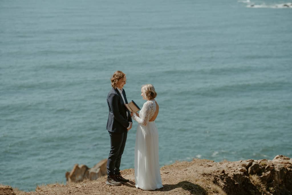 couple reading vows while eloping at the oregon coast